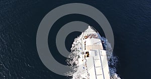 White motor boat with tourists at the stern floats on the sea. Top view