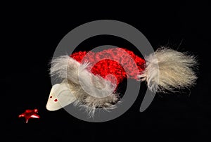 A white mouse from marshmallow is coming out of a red jelly bag cap in front of black background, sniffling on a star photo
