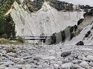 White mudstone cliffs and road bridge on Mangaweka river in New Zealand