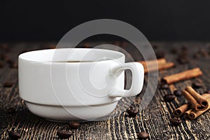 a white mug with a black drink and coffee beans