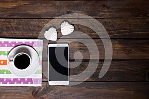 White mug of coffee and two marshmallows in the shape of hearts on a wooden background for breakfast