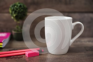 White mug mockup. Blank mug. Coffee mug mockup with bright neon colors pencils and notebooks. Potted plant bonsai behind