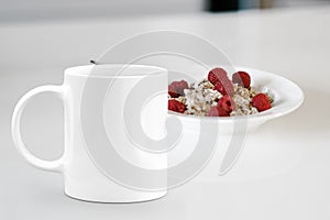 White mug next to a bowl of cereal.