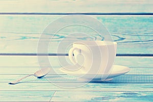 White mug with saucer and tea spoon on a blue background