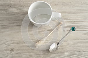 A white mug with a sugar stick and a teaspoon