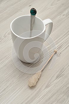 A white mug with a sugar stick and a teaspoon