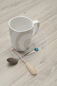 A white mug with a sugar stick and a teaspoon