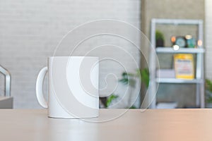 White mug on table and modern room background. Blank drink cup for your design. Can put text, image, and logo