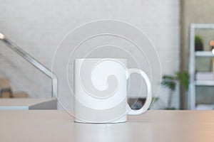 White mug on table and modern room background. Blank drink cup for your design. Can put text, image, and logo