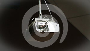 White multimedia projector hanging from a ceiling mount