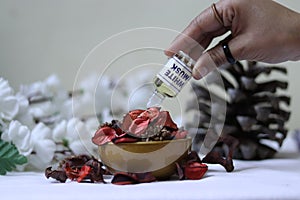 White Musk being pored on pot pourri with pine & flowers the background