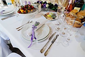 White napkin with purple flowers on a white empty plate on a dining table. Table setting. Table served for edding dinner. photo