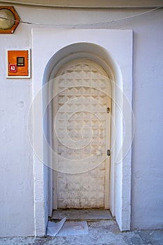 A white narrow door in a Turkish house with an arch and a window