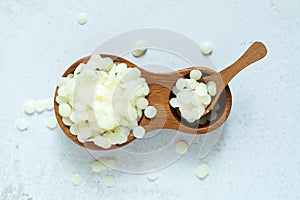 White natural beeswax pellets in wooden plate