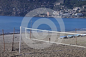 White net and empty beach volleyball court against the backdrop of the sea and urban development, Alanya, November 2021