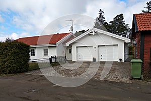 White new garage for two cars and wooden barn on private house yard