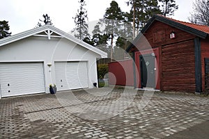 White new garage for two cars and wooden barn on private house yard