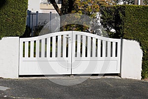 White new metal driveway entrance home gates in modern suburb house