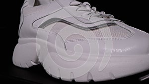 White New Sneaker Rotates on a Black Background. Sport Female Shoes