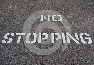 White No Stopping Sign Stenciled on Black Road