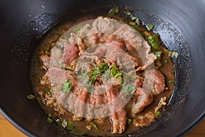 White noodle soup with meatball and beef stewed served in a black bowl. In Thailand, we call this food