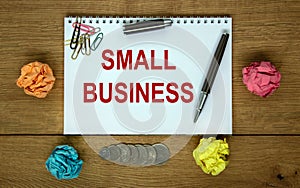 White note with inscription `small business` on beautiful wooden table, colored paper, metalic pen. Business concept