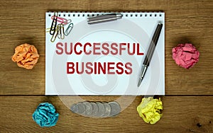 White note with inscription `successful business` on beautiful wooden table, colored paper, metalic pen. Business concept