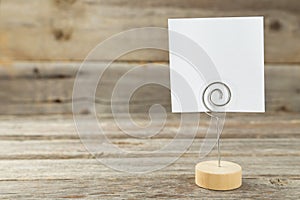 White note paper on a holder on grey wooden background.