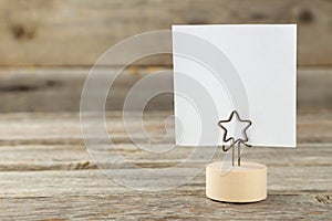 White note paper on a holder on grey wooden background.