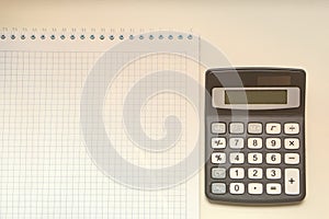 White notebook and digital calculator on a white table, isolate