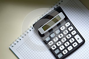 White notebook and digital calculator on a white table, isolate