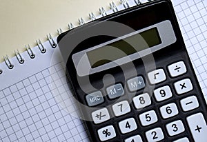 White notebook and digital calculator on a white table, isolate