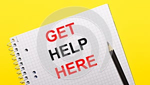 White notebook with inscription GET HELP HERE written in black pencil on a bright yellow background