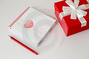 A white notebook and a red pen lie on a white table