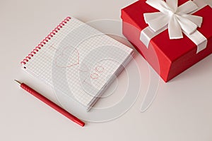 A white notebook and a red pen lie on a white table