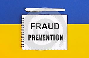 A white notebook with the text FRAUD PREVENTION and a white pen on a blue and yellow background