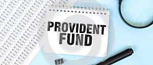 White notepad and magnifier on the financial documentation. Text PROVIDENT FUND. Business concept