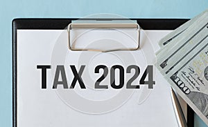 White notepad and magnifier on the financial documentation. Text TAX 2024. Business concept