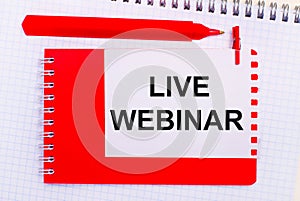 On a white notepad, a red pen, a red notepad and a white sheet of paper with the text LIVE WEBINAR