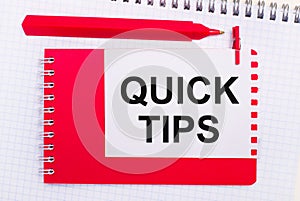 On a white notepad, a red pen, a red notepad and a white sheet of paper with the text QUICK TIPS