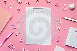 white notepad sheet on a pink background. Back to school, school supplies, top view