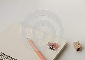 White notepad with spiral and stick pencil, with wooden sharpener