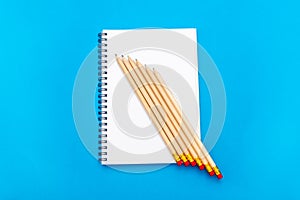 White notepad with steel pen on a blue background. Office table, minimal composition. Copy space