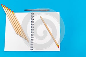 White notepad with steel pen on a blue background. Office table, minimal composition. Copy space