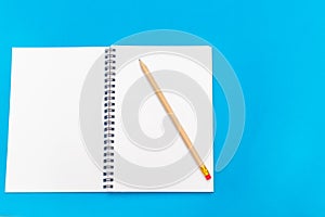 White notepad with steel pen on a blue background. Office table, minimal composition. Copy space