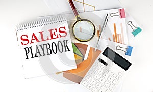 White notepad text SALES PLAYBOOK with diagram,chart,calculator on the white background