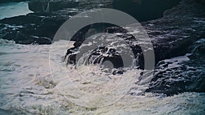 White ocean washing rocks on storm day. Closeup foaming waves hitting coastline