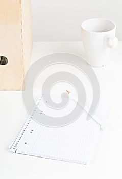 White office desk with empty notepad, pencil, cup and folders