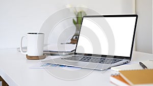 White office desk with laptop computer, document, notebook and coffee cup. Empty screen for your advertise text