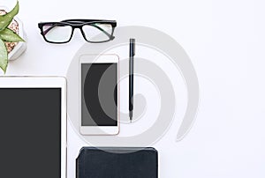 White office desk with notebook, tablet, smartphone, glasses and pen. Blank mobile phone and notepad for input text. Business,